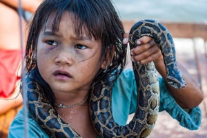 Orphanage tourism and slavery. Tonle Sap, Siem Reap, Cambodia: A little girl making money for her family by posing with a snake in a water village of Tonle Sap Lake. Source: CEphoto, Uwe Aranas https://commons.wikimedia.org/wiki/User:Cccefalon via Wikimedia https://commons.wikimedia.org/wiki/File:Tonle_Sap_Siem_Reap_Cambodia_Girl-begging-for-money-with-snake-01.jpg