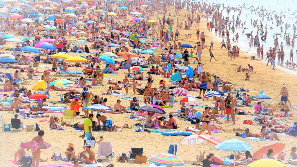 Overtourism leads to overcrowding. What to do? Bans? Entrance fees? (Image by pierrelaurentdurantin via Pixabay cropped and enhanced by "GT".) https://pixabay.com/en/beach-world-sun-crowd-654641/