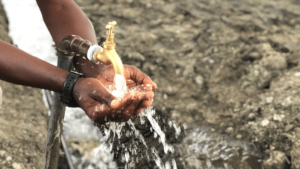 Fresh water runs from a newly-installed tap into the cupped hands of a Tanzanian man