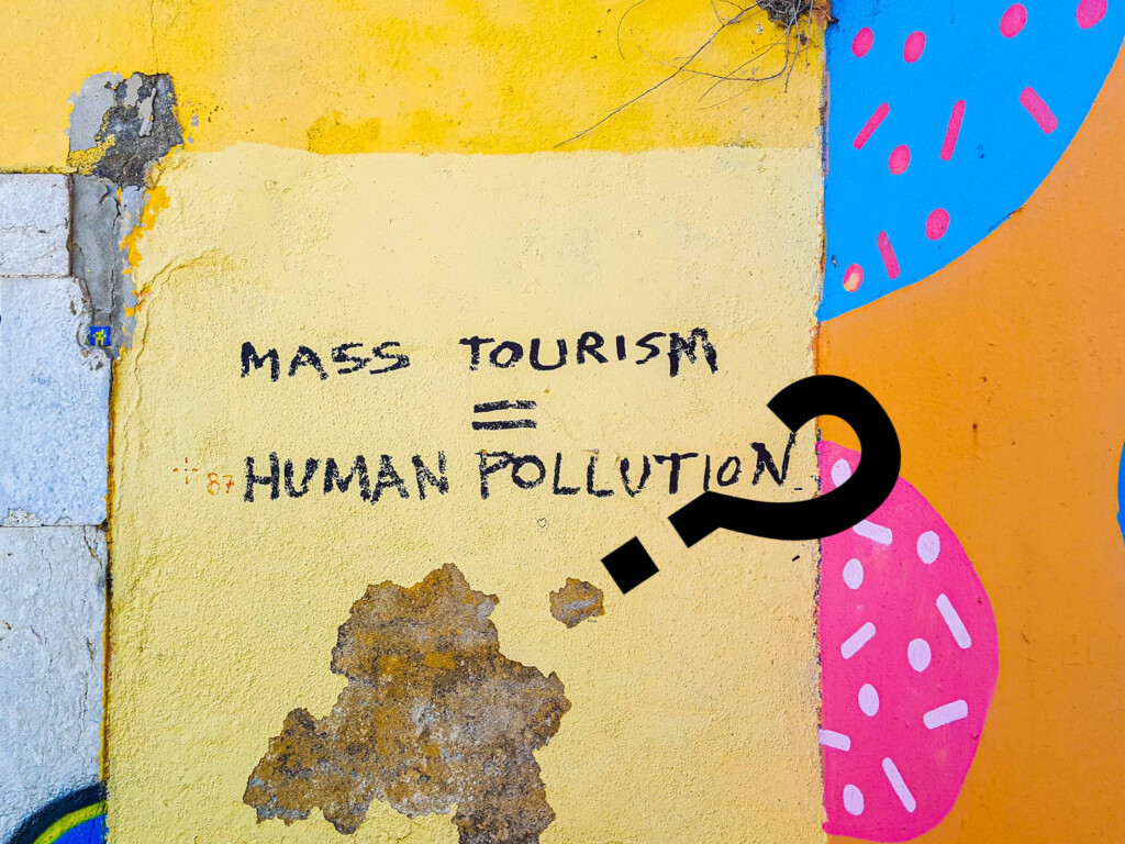 What is 'mass tourism'? Is it "human pollution" as this graffiti asserts? Image by Mark de Jong (CC0) via Unsplash. https://unsplash.com/photos/FZ8ZEeL0l8g