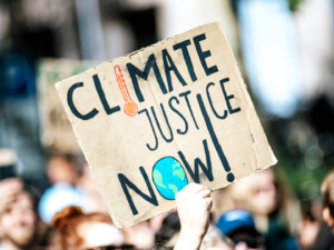 ‘Climate Justice’ in tourism shouldn’t be too hard and it’s the right thing to do. Image by Markus Spiske (CC0) via Unsplash. https://unsplash.com/photos/people-gathered-outside-buildings-holding-climate-justice-now-signage-dYZumbs8f_E